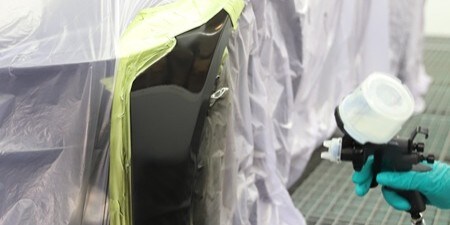Technicien polissant un panneau de carrosserie
