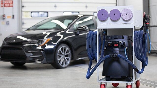 Chariot de ponçage et extraction de poussière 3M dans un atelier avec voiture à l'arrière

