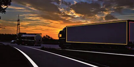 Camion sur une route sombre avec des marquages haute visibilité
