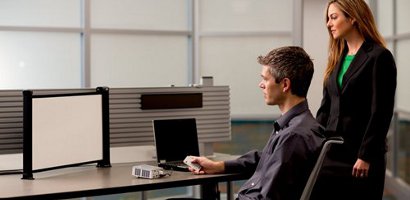 Man sitting, woman standing in front of computer
