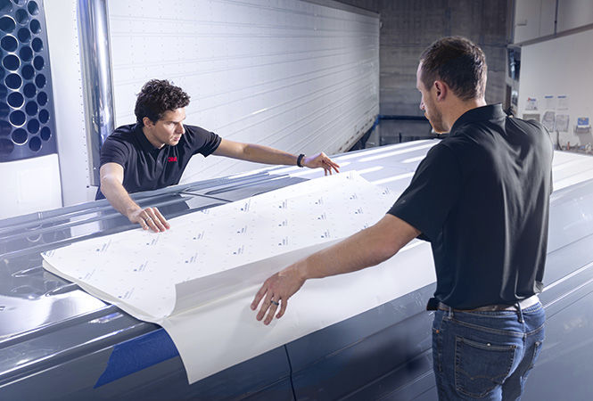 Techniciens posant le film 3M sur le toit d’un véhicule à l’intérieur de la zone de service.
