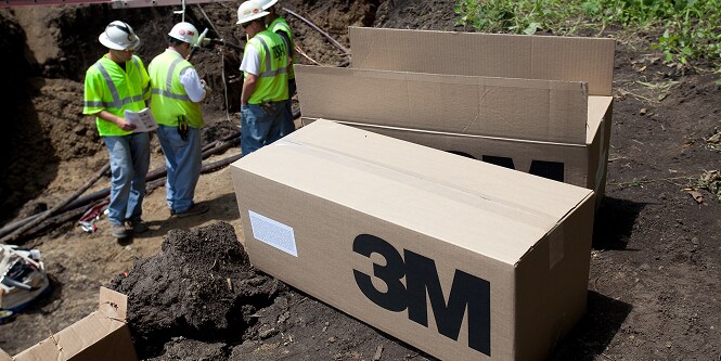Des cartons contenant des produits 3M posés par terre près des opérateurs
