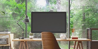 Moniteur sur un bureau, avec une forêt visible en arrière-plan
