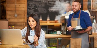 Femme assise dans un café travaillant sur son ordinateur portable

